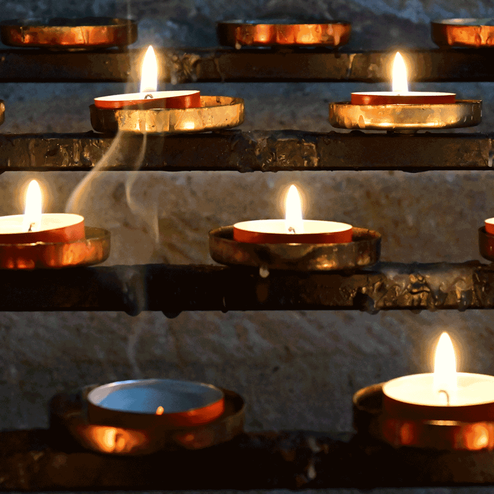 Just expired candle surrounded by several lit candles