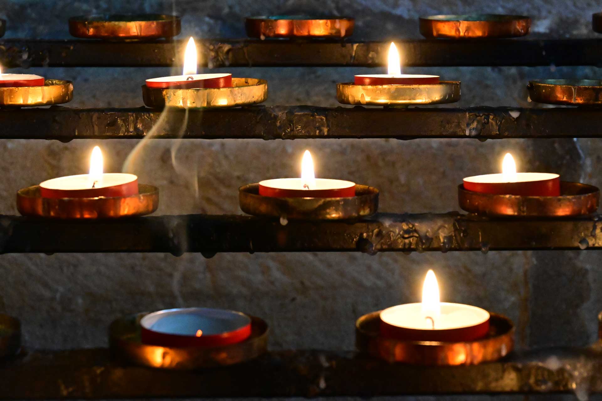 Recently expired candle flame surrounded by lit candles