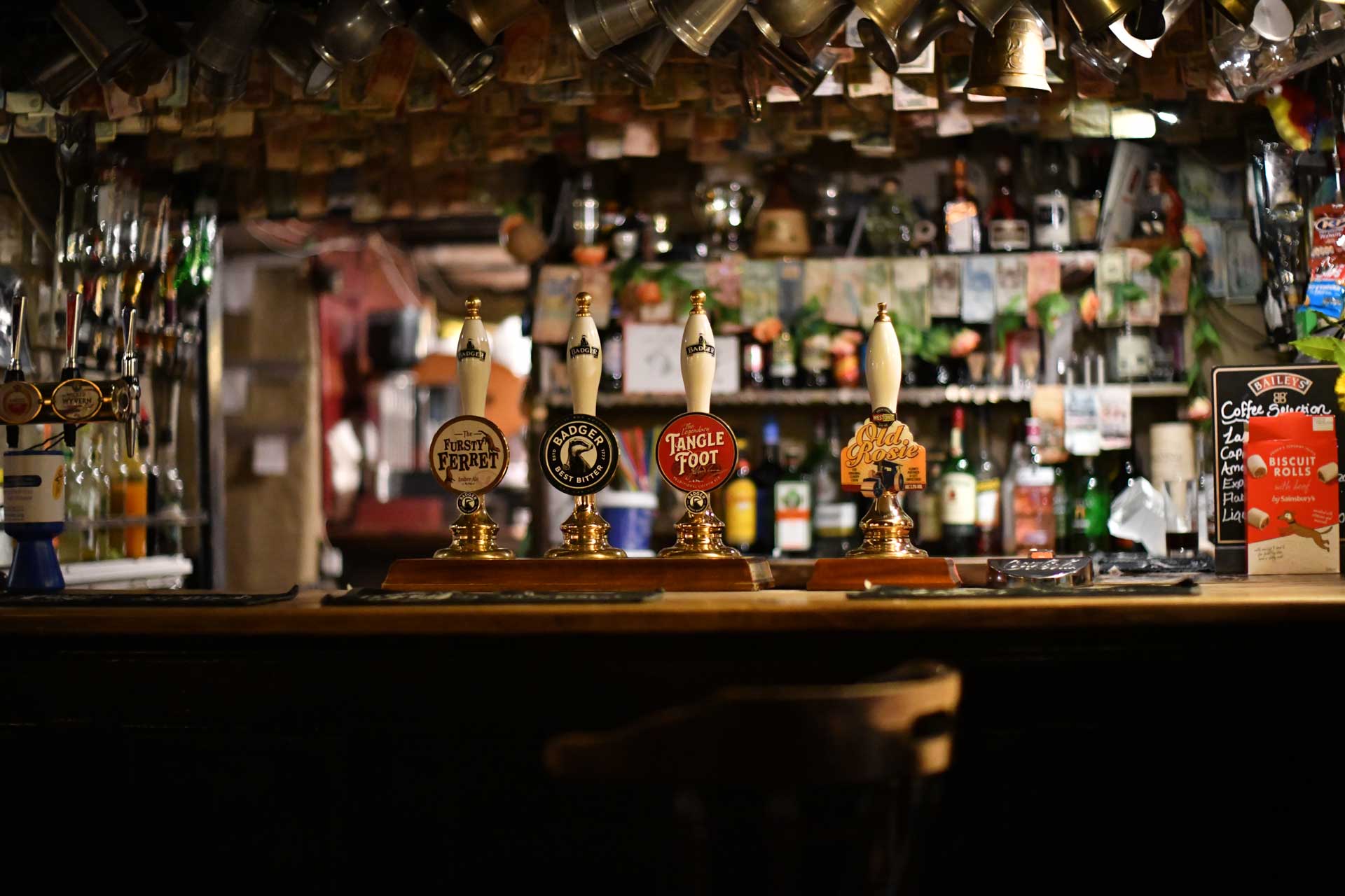 Friendly English pub, showing bar, pumps, pewter mugs and seat etc.