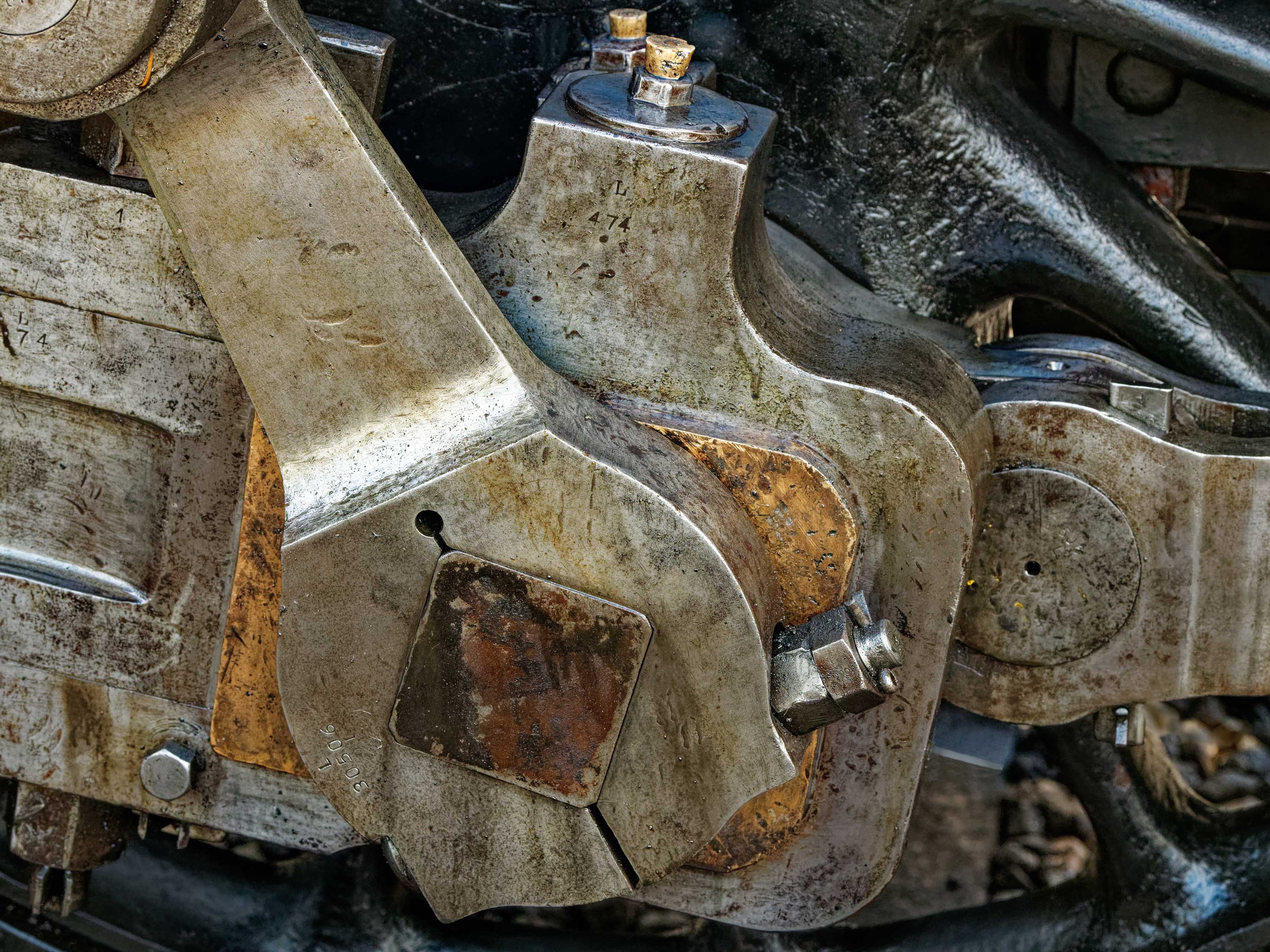 Close-up picture of the oily connecting rod driving the wheel of a mainline steam locomotive.