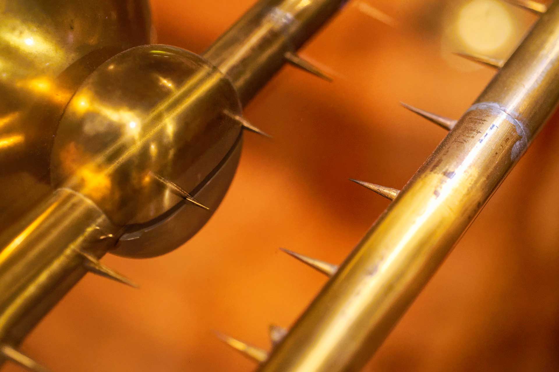 Close-up of a scientific apparatus for generating static electricity, showing a double row of sharp spikes.
