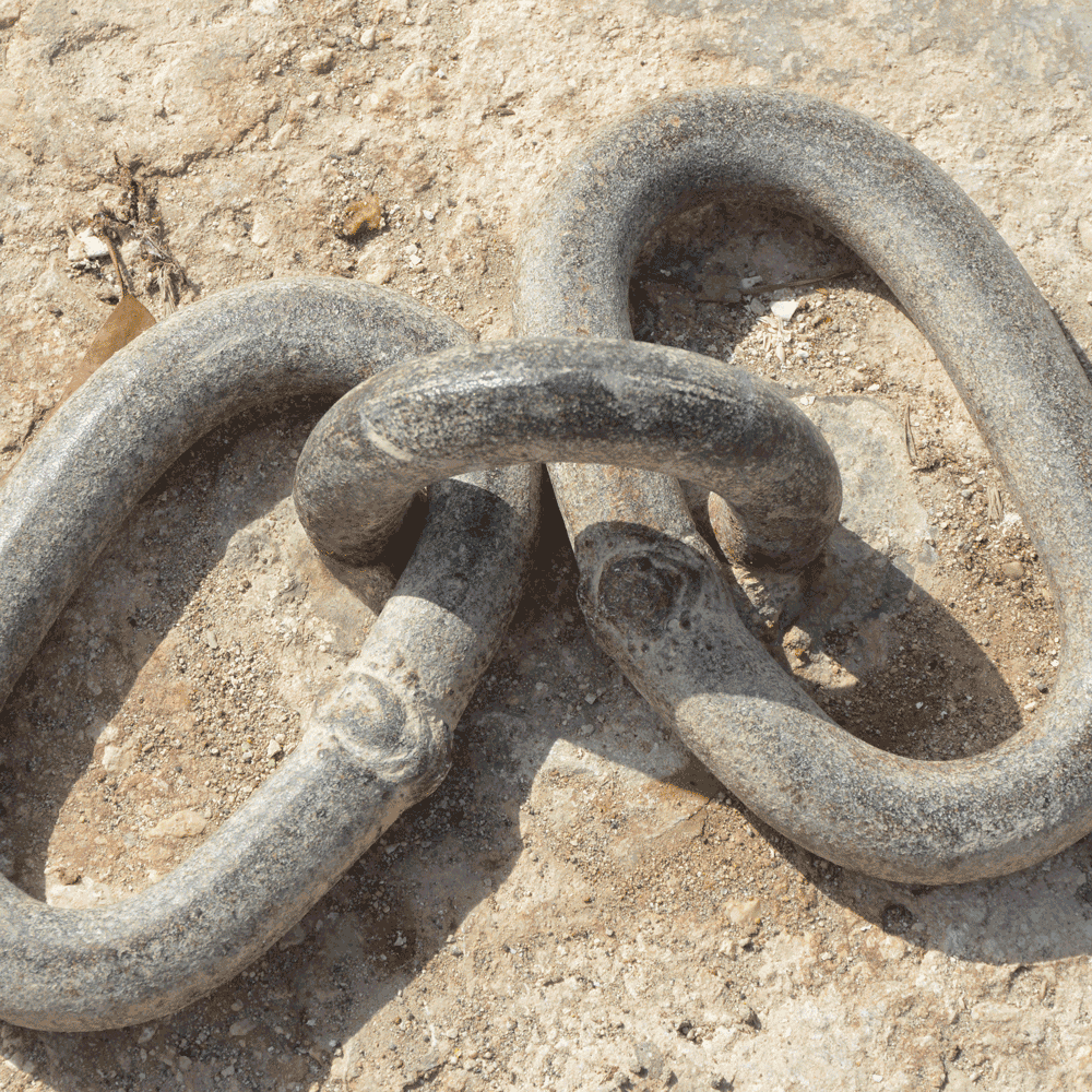 Two large chain links joined to a heavy duty eyelet set in concrete.