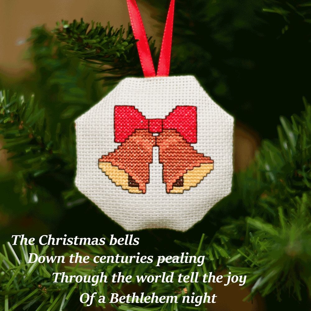 Cross-stitched octagonal picture of two church bells, hanging in a Christmas tree.
